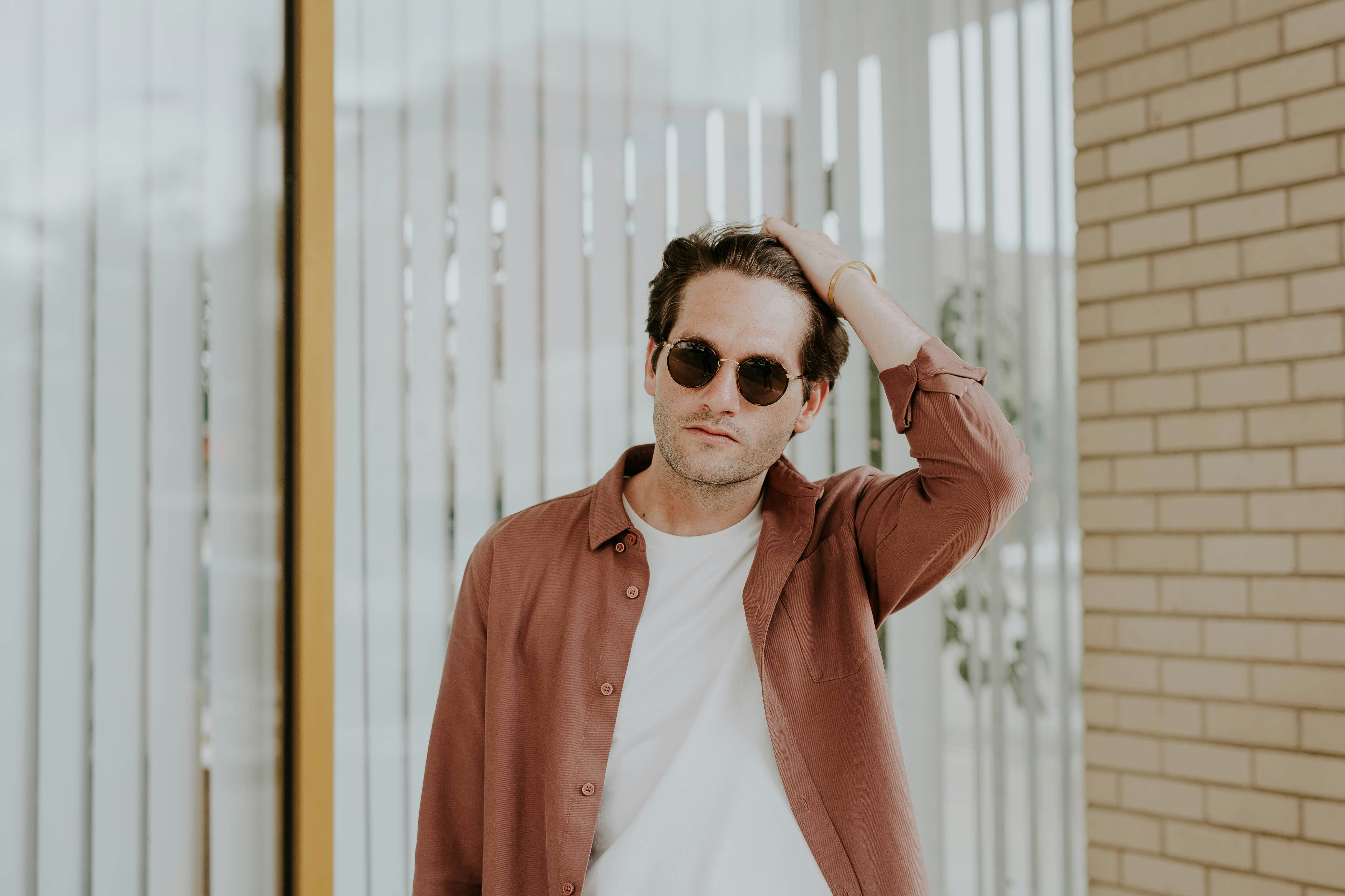 man in brown jacket near window blinds